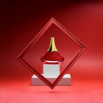 Foto de perfume de frasco vermelho e tampa dourada com moldura e fundo vermelho. Por Gilson Reis Fotografia.