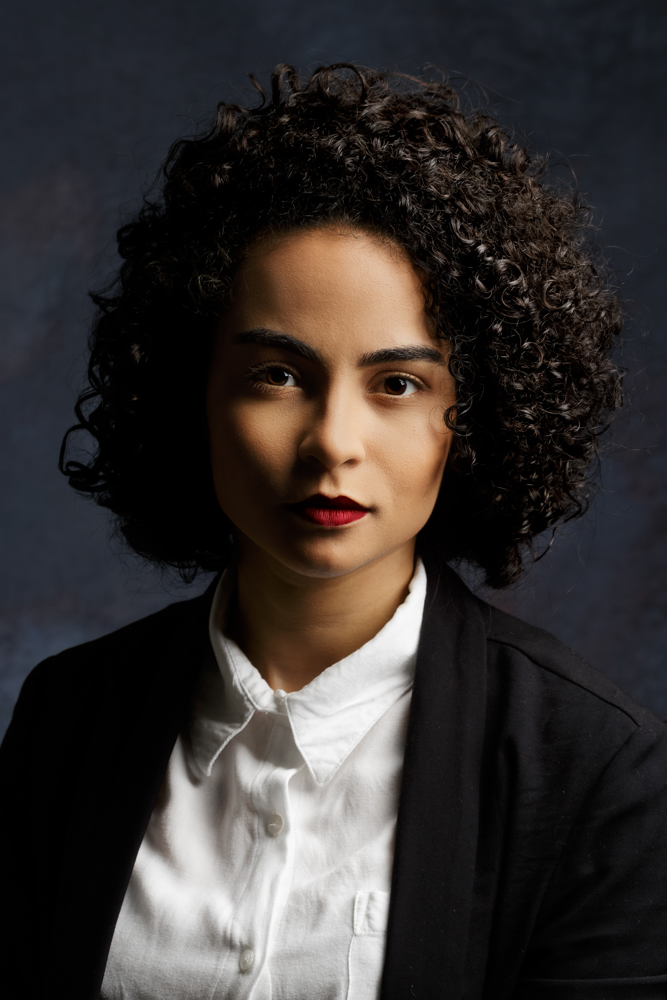 Retrato feminino de estúdio com cabelo cacheado e fundo escuro