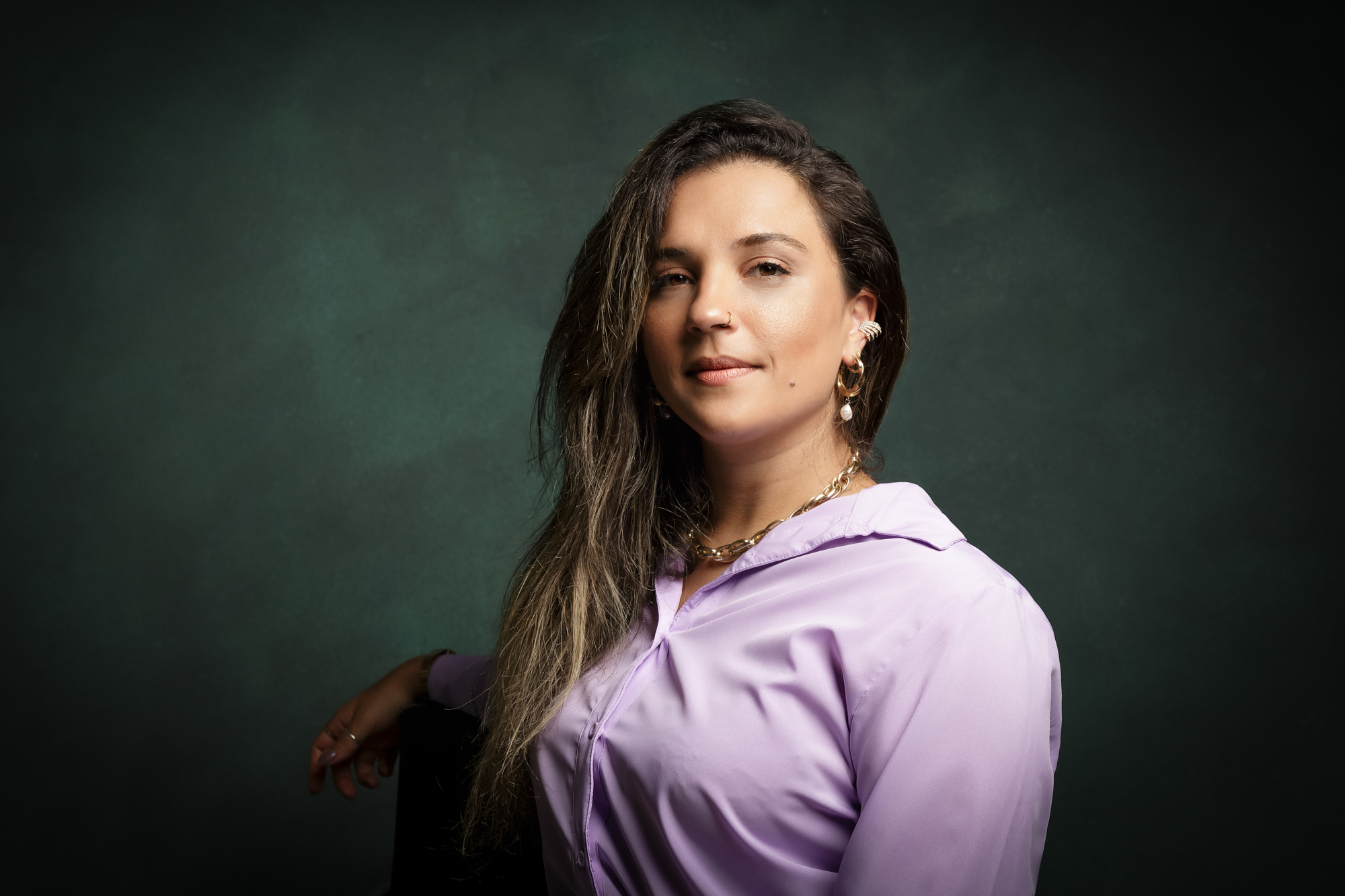 Retrato feminino com brincos em fundo verde e iluminação de estúdio