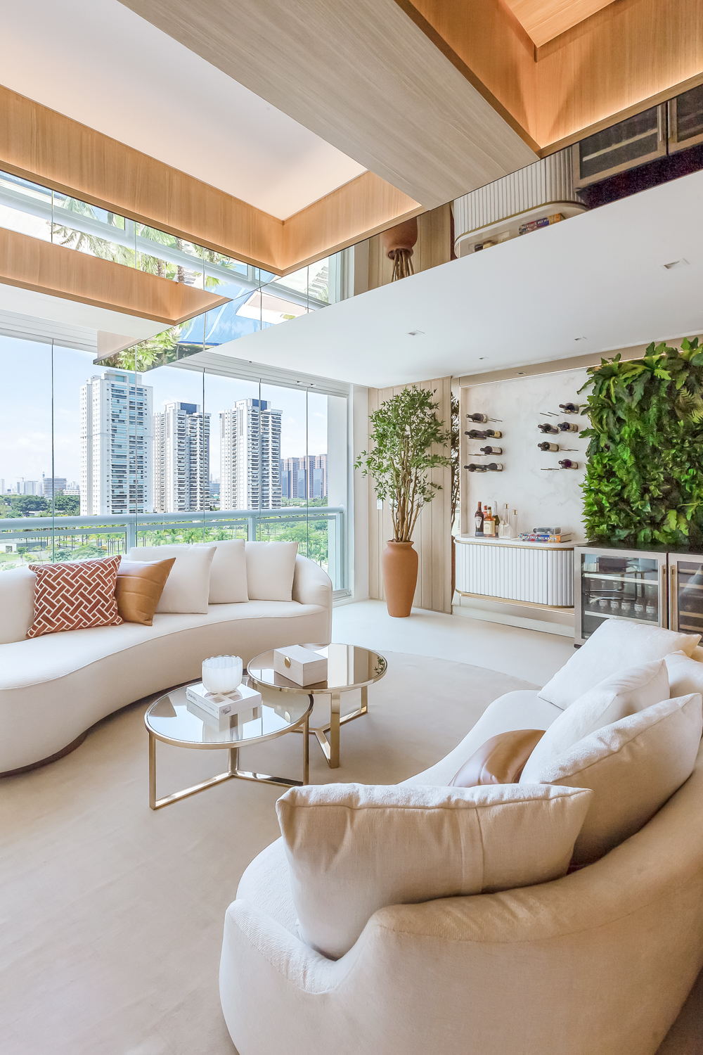 Sala residencial integrada à varanda com mobiliário claro, plantas e vista urbana.