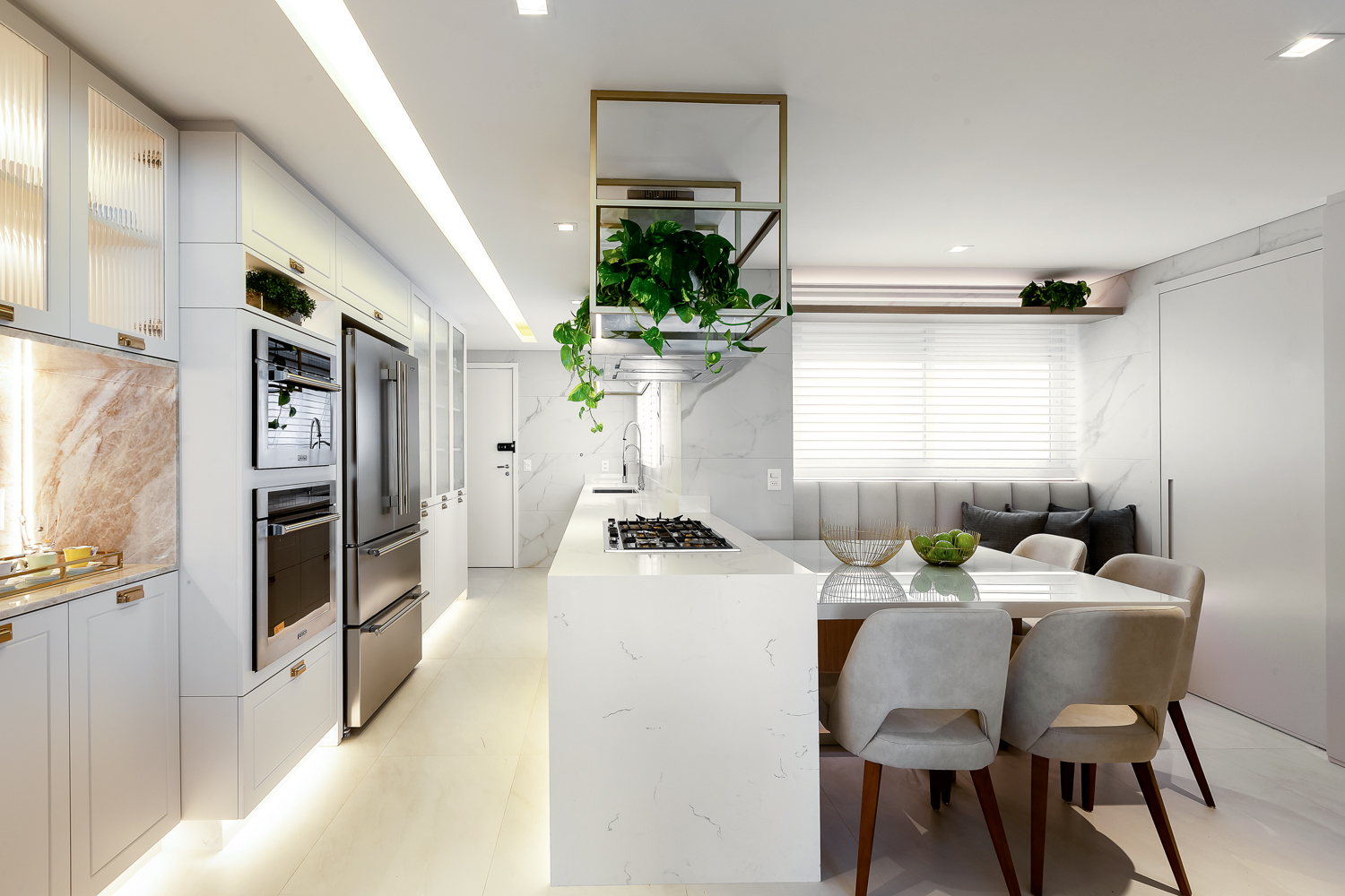 Cozinha integrada com armários brancos, bancada escura e plantas decorativas.