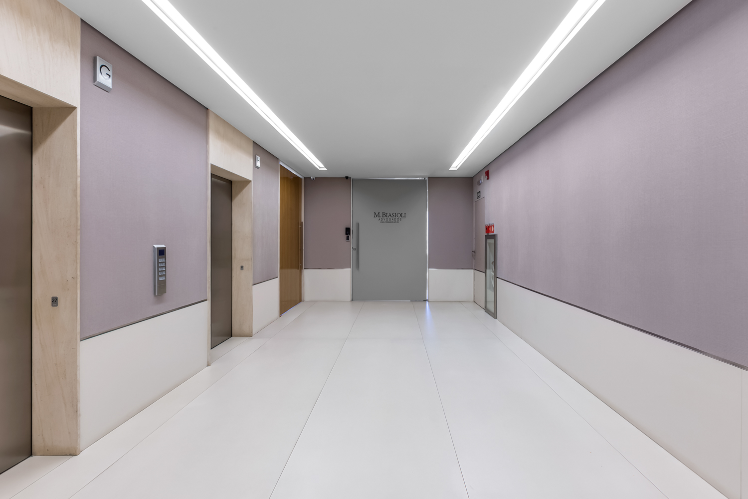 Corredor residencial com marcenaria cinza, portas alinhadas e iluminação linear no teto.