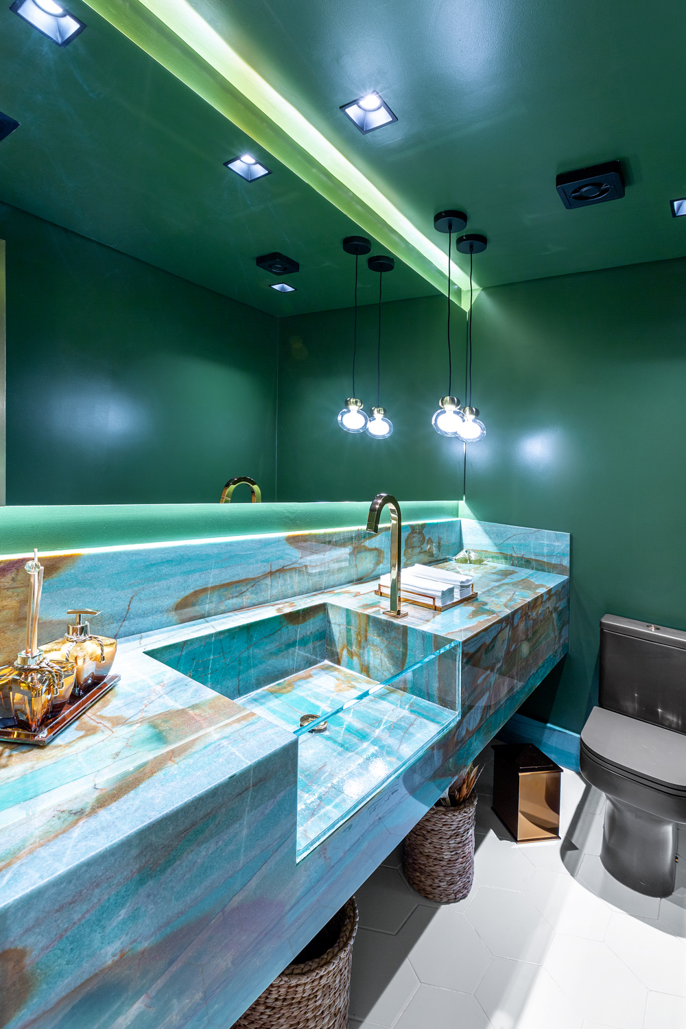 Cozinha contemporânea verde com ilha central, bancada clara e iluminação pendente.