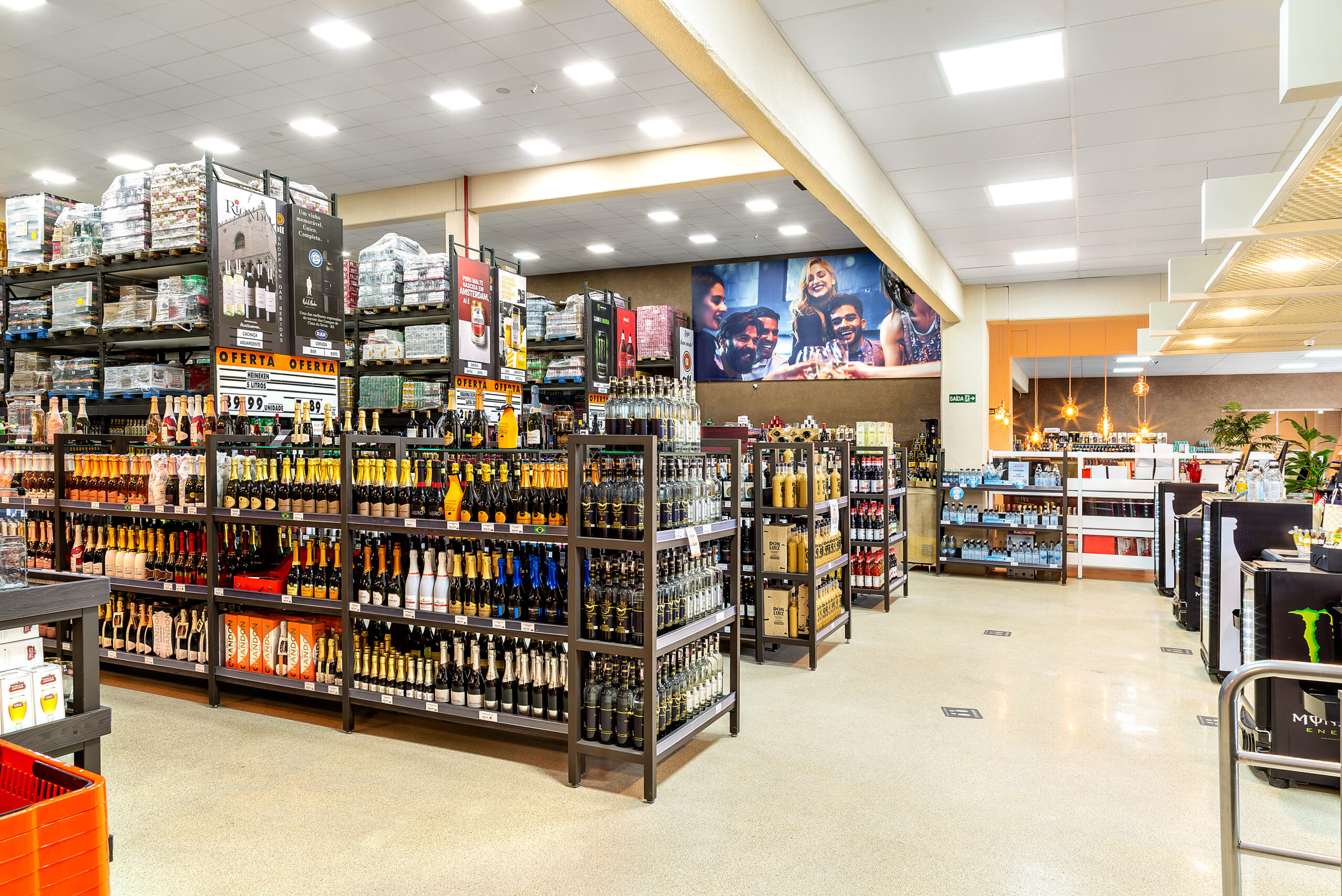 Corredores internos de supermercado com gôndolas organizadas e iluminação no teto.