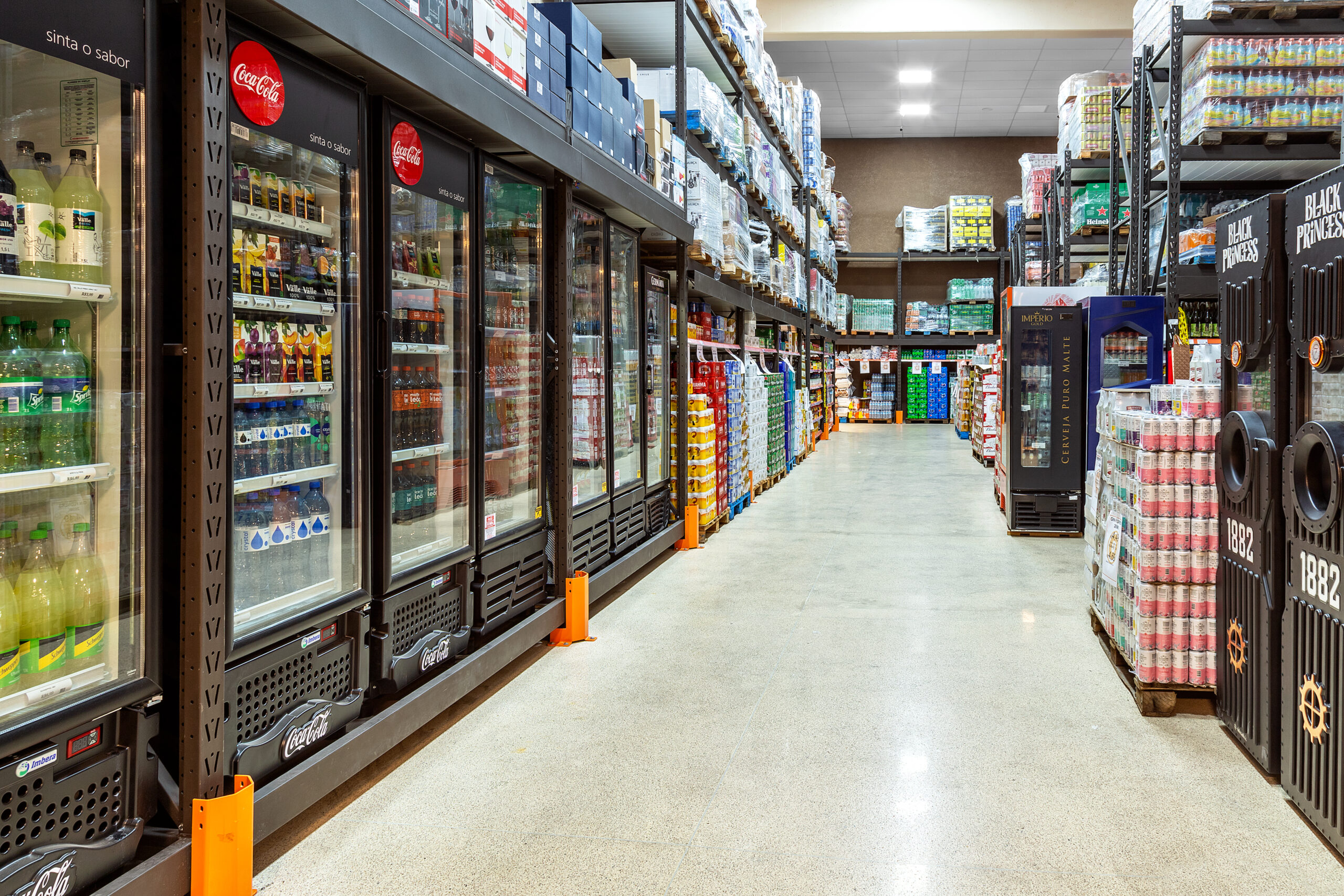 Corredor de supermercado com expositores refrigerados e iluminação linear.