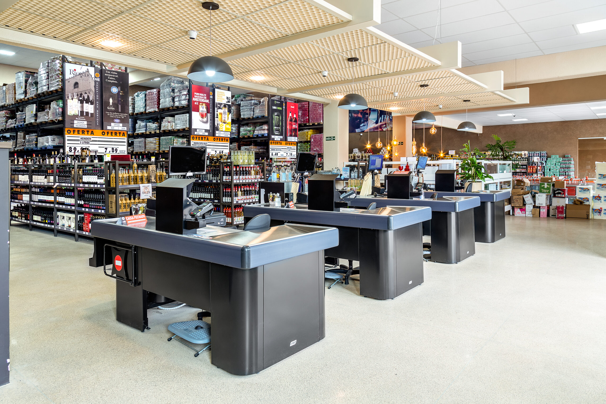 Área de caixas de supermercado com balcões alinhados, iluminação uniforme e ampla circulação.