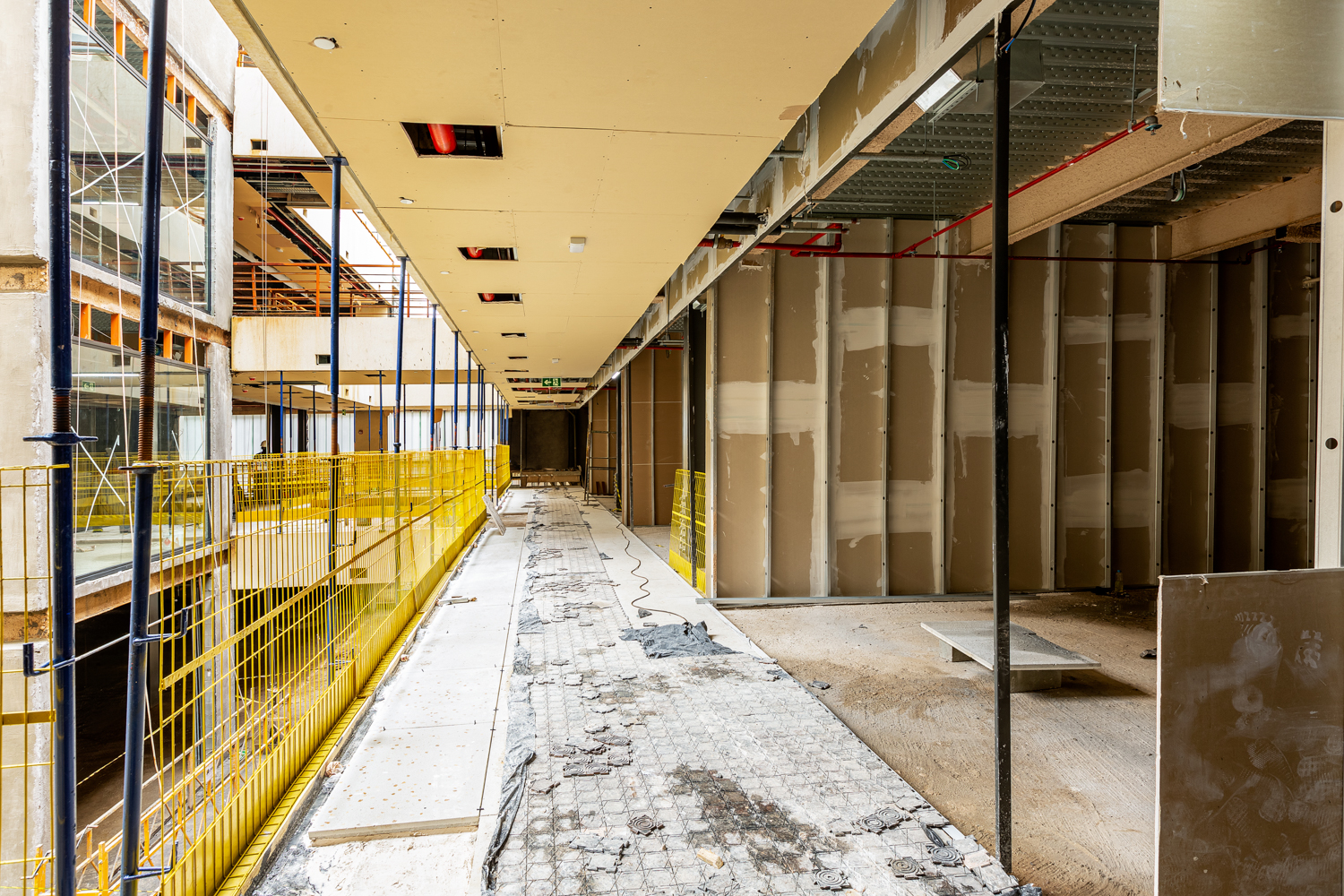 Passarela interna de empreendimento em construção com estrutura metálica e concreto aparente.